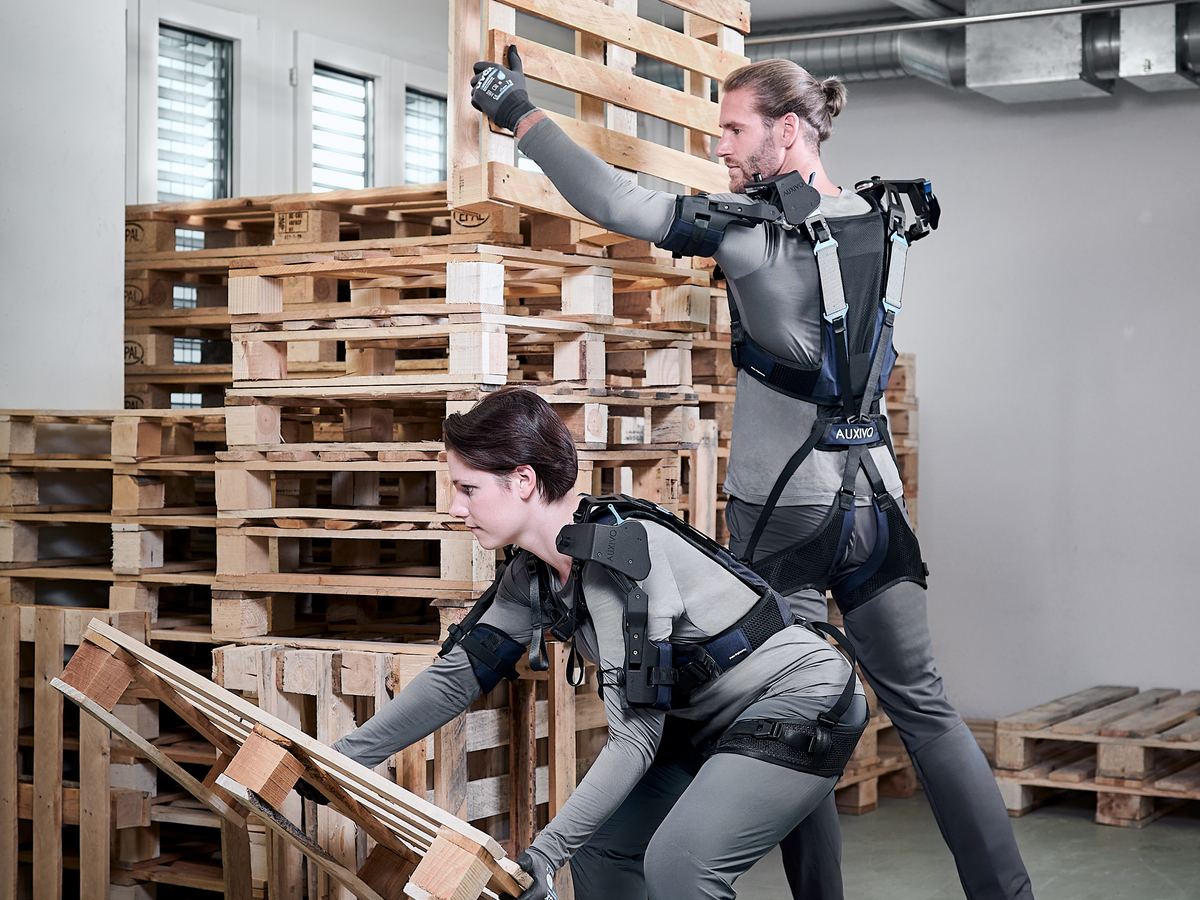 Két dolgozó Auxivo OmniSuit exoskeletonban raklapokat pakol
